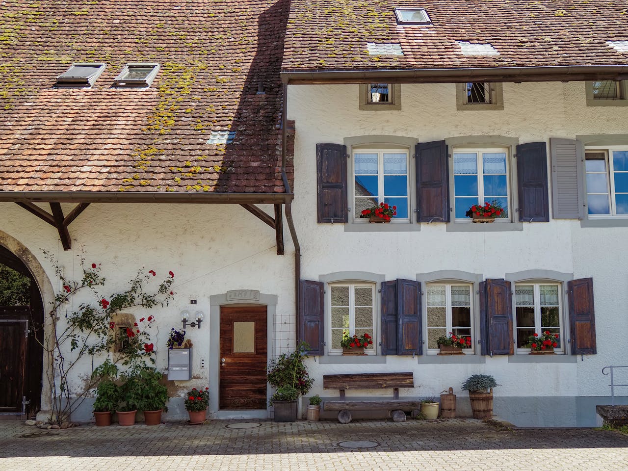 Rustic Swiss bed and breakfast with wooden shutters and flower boxes, perfect for traveling charm seekers.